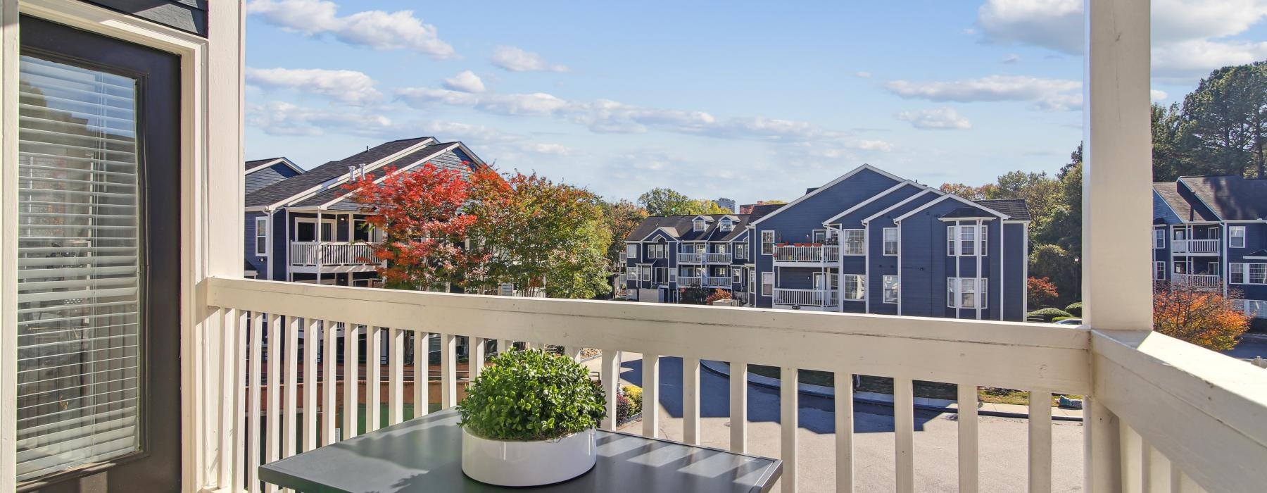 a balcony with a table and a plant on it and a building in the background